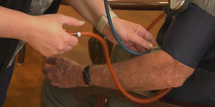 An RN checks a resident's blood pressure.
