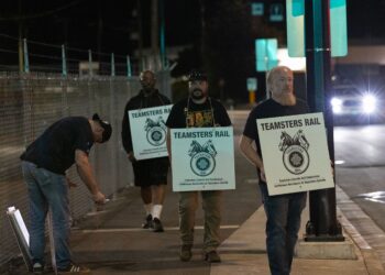 (Andrew Chin/Getty Images via CNN Newsource) Teamsters union members hold picket signs at the entrance of CN Rail Lynn Creek Yard in North Vancouver, British Columbia, Canada.