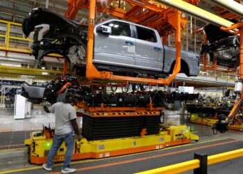 (Jeff Kowalsky/AFP/Getty Images via CNN Newsource) The truck cab is lowered on the frame of Ford Motor Co. battery powered F-150 Lightning trucks.