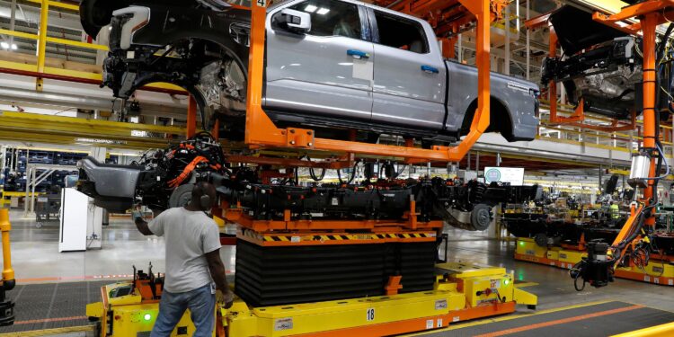 (Jeff Kowalsky/AFP/Getty Images via CNN Newsource) The truck cab is lowered on the frame of Ford Motor Co. battery powered F-150 Lightning trucks.