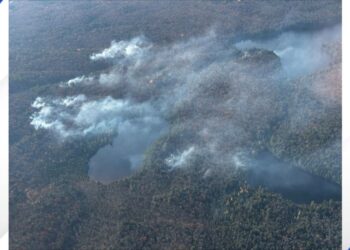 (Courtesy: U.S. Forest Service - Ottawa National Forest) USDA Forest Service taken on October 21, 2024 the fire view from the air yesterday and crews on the ground waiting safely out of the way for air tankers to drop water on the fire.