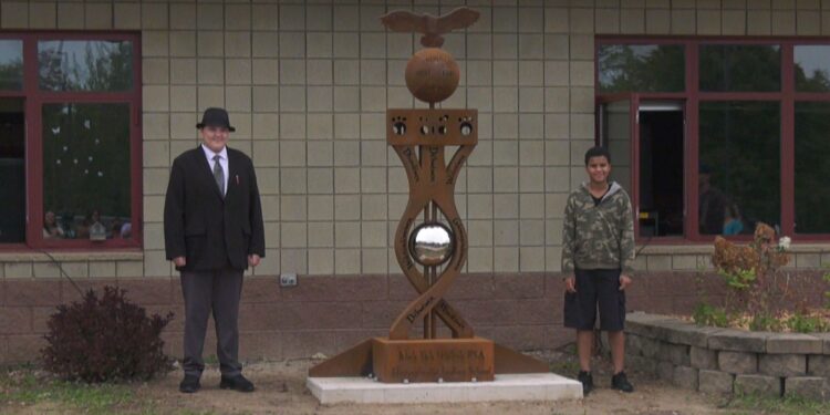 Student designers James Johnsen and Izayah Harris pose with the sculpture
